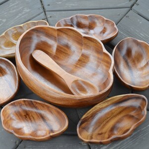 May include: Set of six wooden bowls in a variety of sizes and shapes, with a wooden serving spoon. The bowls are all made of a light brown wood and have a natural, rustic look.