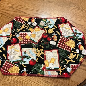 Puede incluir: Mantel individual hexagonal negro con borde a cuadros rojos. El mantel individual presenta ilustraciones de pasta, tomates, ajo, aceite de oliva y tarjetas de recetas. El diseño incluye varias formas de pasta y elementos italianos.