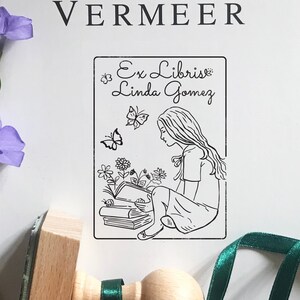 Girlish Bookplate Stamp. Unique stamp's illustration shows the longhaired girl sitting above the books and reading one. There are flowers and butterflies around. A premium quality stamp with the knob on top of the wooden handle.