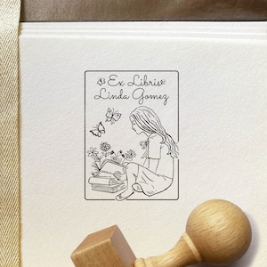 A Girl reading the book Personalized Exlibris Stamp. Unique stamp's illustration shows the longhaired girl sitting above the books and reading one. Imagination creates the images of flowers and butterflies. High-quality Wooden Stamp with the knob