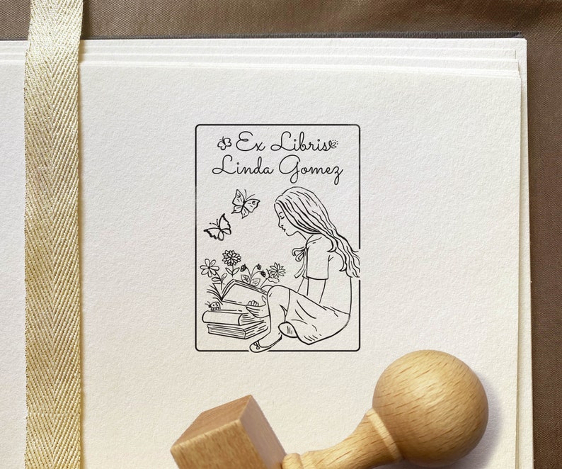 A Girl reading the book Personalized Exlibris Stamp. Unique stamp's illustration shows the longhaired girl sitting above the books and reading one. Imagination creates the images of flowers and butterflies. High-quality Wooden Stamp with the knob