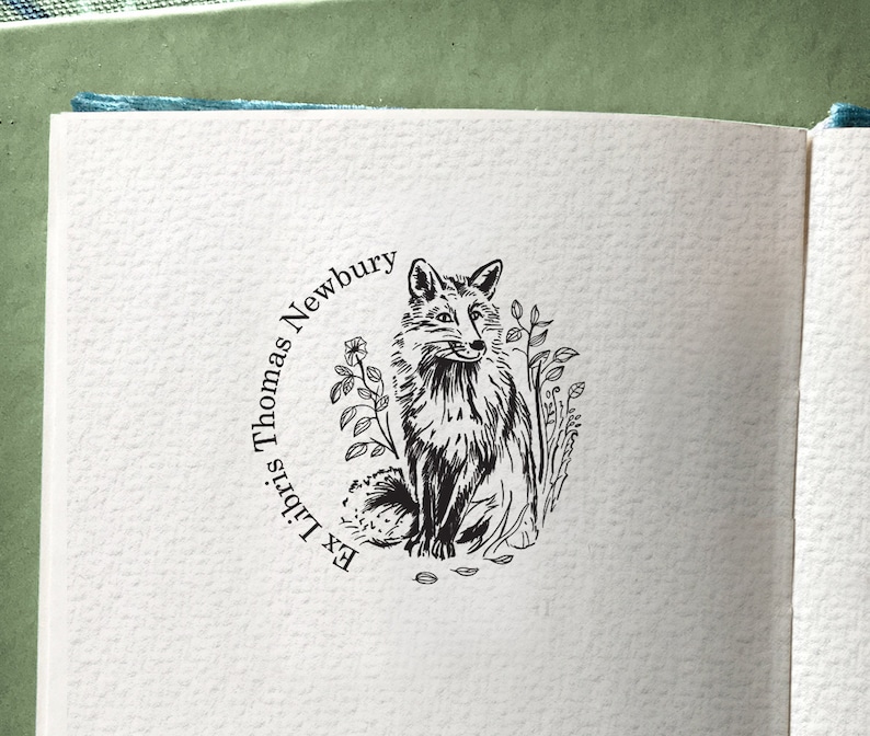 FOX Personalised Ex Libris Wooden Stamp. The illustration depicts a sitting fox in the greens. The style of the drawing is traditional, and vintage. The hand-drawn illustration recalls the one from the old books. The fox looks nice and friendly.