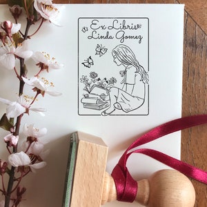 Girlish Bookplate Stamp. Unique stamp's illustration shows the longhaired girl sitting above the books and reading one. There are flowers and butterflies around. A premium quality stamp with the knob on top of the wooden handle.