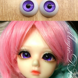 Puede incluir: Un par de ojos de muñeca de color morado con una pupila negra y un iris blanco. Los ojos están sobre una superficie de madera.