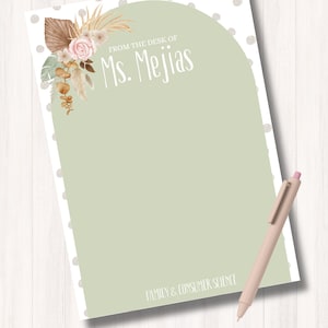 Pode incluir: Um bloco de notas retangular com um design de arco verde sálvia e bolinhas brancas na borda. O texto diz FROM THE DESK OF Ms. Mejias e FAMILY & CONSUMER SCIENCE. Um arranjo floral fica no canto superior esquerdo. Uma caneta está incluída.