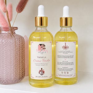 May include: Two clear glass dropper bottles filled with yellow body oil. The front label reads Vanilla Cr&egrave;me Br&ucirc;l&eacute;e + Velvet Body Oil, 3.38 FL OZ (100 ML). The back label features text including A Little Luxury and ingredients list.