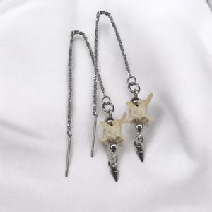 May include: A pair of silver dangle earrings with bone-shaped charms and silver chain drops.