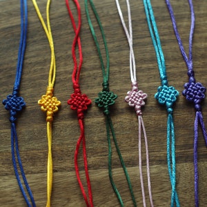 May include: Eight colorful knotted cords with flower-shaped knots at the end. The cords are blue, yellow, red, green, pink, turquoise, and purple.