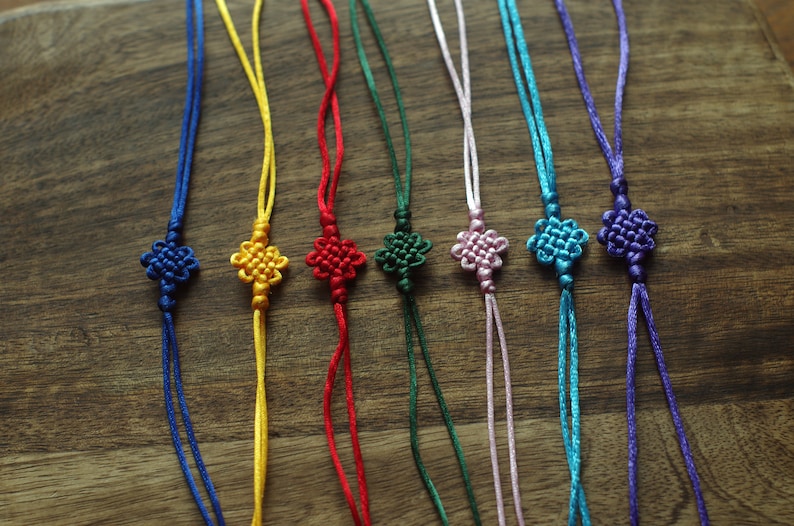 May include: Eight colorful knotted cords with flower-shaped knots at the end. The cords are blue, yellow, red, green, pink, turquoise, and purple.