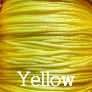 May include: A close-up of a spool of bright yellow thread. The word "Yellow" is printed in white on the spool.