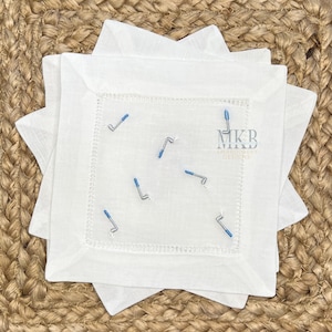 May include: White linen napkins with blue embroidered golf clubs and the text "MKB Embroidery Designs".