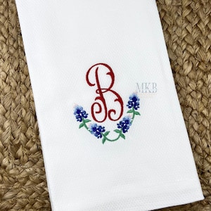 May include: White kitchen towel with a red embroidered letter B surrounded by blue and white embroidered flowers. The text "MKB" is embroidered in the top right corner.