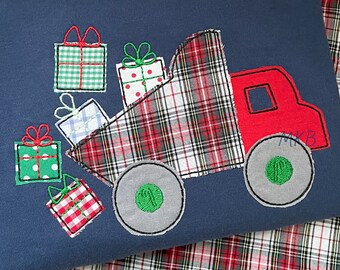 May include: A blue and red plaid truck carrying a stack of wrapped Christmas presents. The truck has a red cab and gray wheels. The presents are wrapped in red and green plaid paper.
