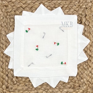 Könnte beinhalten: Set aus vier weißen Leinen-Servietten mit gestickten Golfclub- und Flaggen-Designs. Die Servietten tragen den Text "MKBEmbroidery Designs".