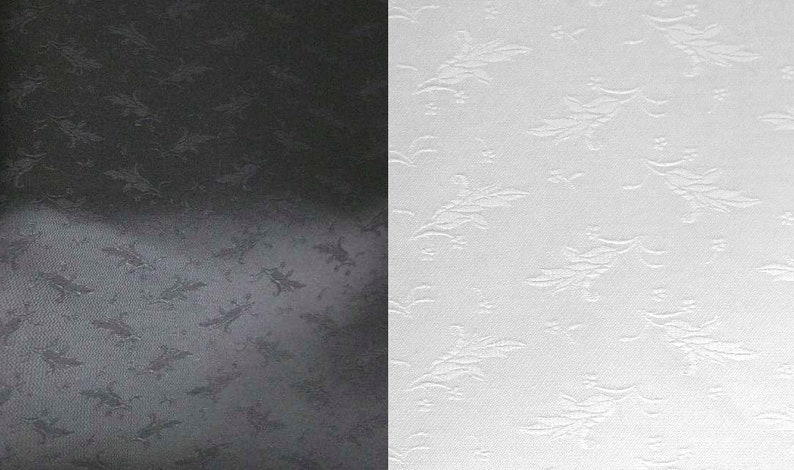 May include: A split image showcasing two fabric samples. One side is black, the other is white. Both have a repeating embossed floral pattern. The texture is visible, with the design slightly raised from the surface.
