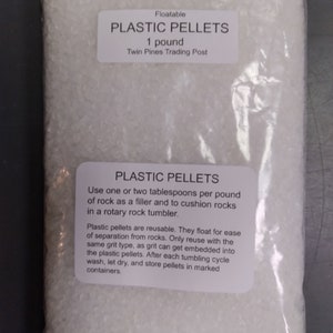 May include: A clear plastic bag filled with white plastic pellets. The bag has a label that reads "Floatable Plastic Pellets 1 pound Twin Pines Trading Post". The label also includes instructions for using the pellets in a rock tumbler.
