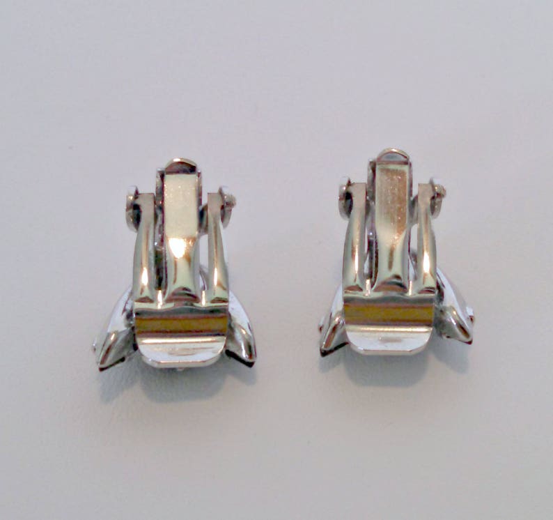 May include: A pair of silver clip-on earrings with a clear stone in the center of each earring.