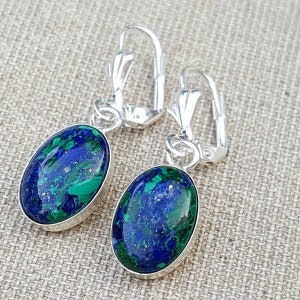 May include: A pair of silver earrings with oval-shaped blue and green gemstone drops. The earrings have a lever back closure.