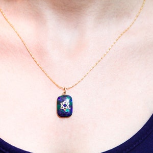 May include: A gold chain necklace with a pendant featuring a blue and green stone with a gold Star of David design.