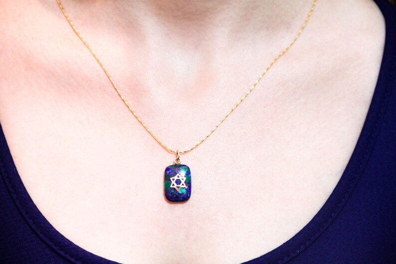 May include: A gold chain necklace with a pendant featuring a blue and green stone with a gold Star of David design.