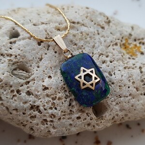 May include: A gold chain necklace with a pendant featuring a blue and green malachite stone with a gold Star of David.