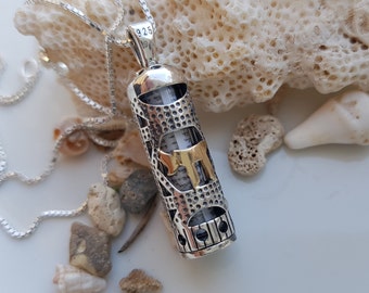 May include: Silver and gold tone necklace with a pendant shaped like a scroll. The pendant has a detailed design and the Hebrew letter 'Shin' in gold.