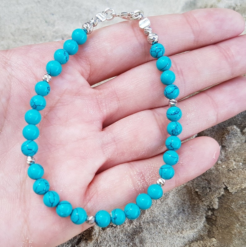 Puede incluir: Un brazalete de cuentas turquesa con detalles plateados. El brazalete est&aacute; hecho de peque&ntilde;as cuentas redondas y tiene un cierre plateado.