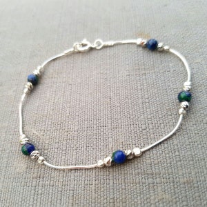 May include: A silver chain bracelet with blue and green gemstone beads.