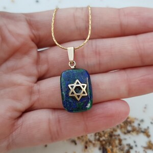 May include: A gold chain necklace with a pendant featuring a blue and green malachite stone with a gold Star of David.