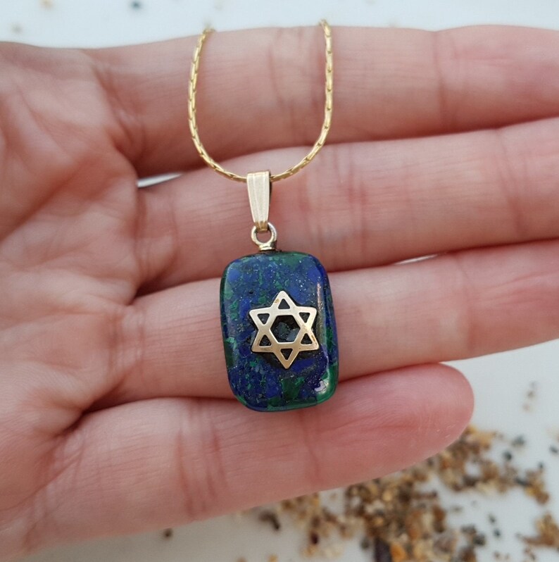 May include: A gold chain necklace with a pendant featuring a blue and green malachite stone with a gold Star of David.