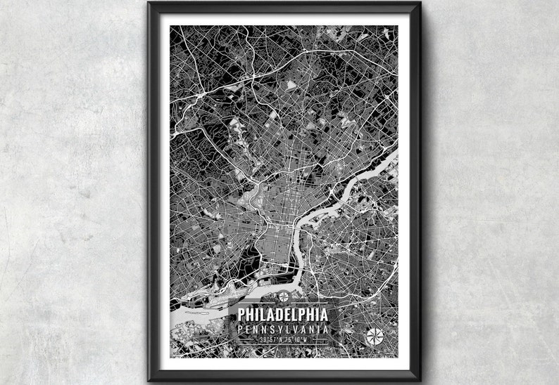 May include: Black and white framed map print of Philadelphia, Pennsylvania. The map shows the city's layout with roads and waterways. The city name and state are printed at the bottom, along with coordinates and a compass rose.