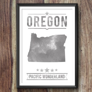 May include: Framed print featuring the state of Oregon in a watercolor style, with the state name above and "Pacific Wonderland" below. The artwork is in shades of gray and white, set against a wooden background.