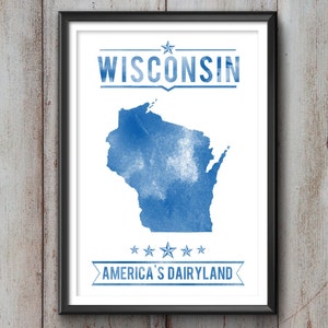 May include: Framed print featuring a blue watercolor map of Wisconsin. The word "WISCONSIN" is above the map, and "AMERICA'S DAIRYLAND" is below. The print is in a black frame and hangs on a wooden wall.