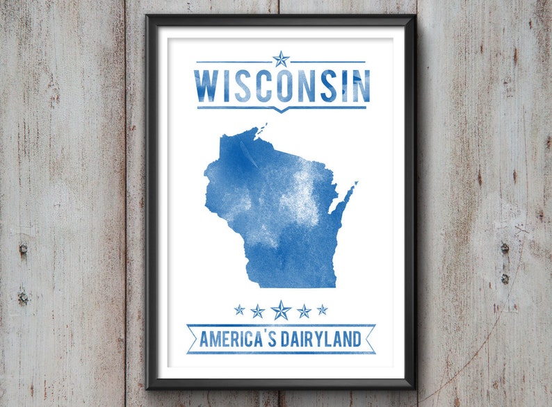 May include: Framed print featuring a blue watercolor map of Wisconsin. The word "WISCONSIN" is above the map, and "AMERICA'S DAIRYLAND" is below. The print is in a black frame and hangs on a wooden wall.