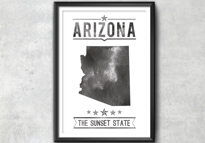 May include: Black and white framed print featuring the state of Arizona. The word "ARIZONA" is printed above the state outline, and "THE SUNSET STATE" is printed below. The print has a watercolor effect.