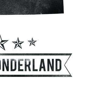May include: A black and white graphic design featuring the word "ONDERLAND" in a rectangular banner with a distressed texture. Above the banner are three black stars, adding a decorative element to the design.