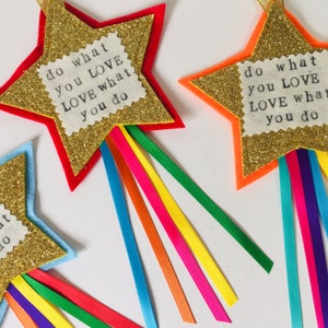 May include: Glittery gold star-shaped decorations with colorful ribbon streamers. Each star has a red, orange, or blue border and a fabric patch with the text "do what you LOVE LOVE what you do."