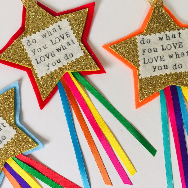 May include: Glittery gold star-shaped decorations with colorful ribbon streamers. Each star has a red, orange, or blue border and a fabric patch with the text "do what you LOVE LOVE what you do."