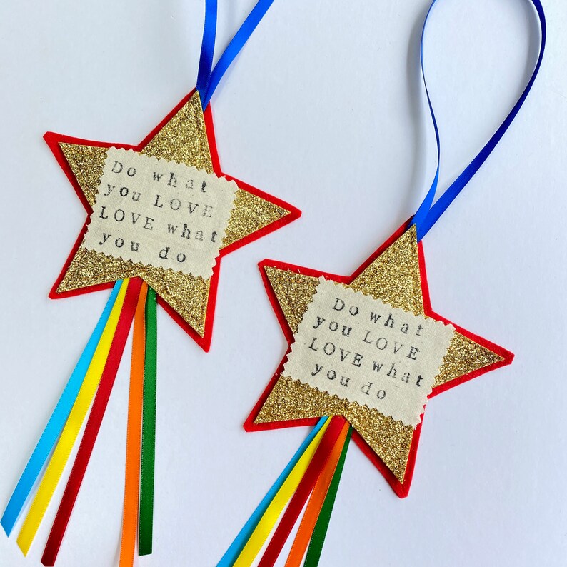 May include: Two star-shaped ornaments with gold glitter, red borders, and blue ribbon hangers. Each has a fabric square with the text "Do what you LOVE LOVE what you do" and rainbow ribbons.