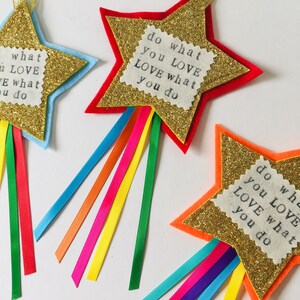 May include: Three star-shaped ornaments with gold glitter centers and colorful felt edges. Each star has a fabric patch with the text "do what you LOVE LOVE what you do" and colorful ribbons.