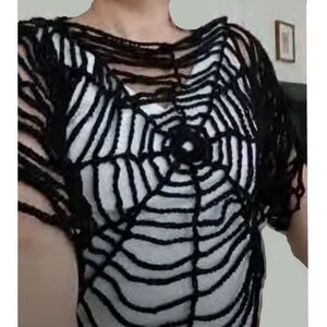 Puede incluir: Un top de crochet negro con un dise&ntilde;o de telara&ntilde;a. El top es holgado y tiene mangas cortas.