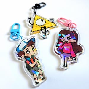 以下が含まれることがあります： アニメシリーズ「Gravity Falls」のキャラクターが描かれた、虹色のキーホルダー3個セット。キーホルダーは、ディッパー・パインズ、メイベル・パインズ、ビル・サイファーの3種類。キーホルダーは透明なアクリル製で、ホログラフィック仕上げです。