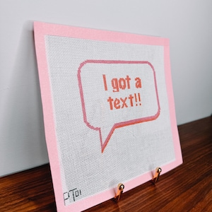 K&ouml;nnte beinhalten: Ein rosa Canvas mit rosa Rand, auf dem eine wei&szlig;e Sprechblase mit dem Text "Ich habe eine SMS!" in Orange zu sehen ist.