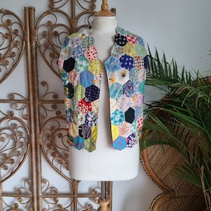 Puede incluir: Un chaleco de patchwork colorido con un patrón hexagonal. El chaleco está hecho de varias telas en tonos de azul, verde, amarillo, rojo y rosa.