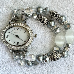 Women’s appealing gray and silver stretch watch bracelet with a smaller, oval watch face surrounded by rhinestones.