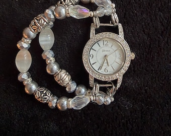 Women’s appealing gray and silver stretch watch bracelet with a smaller, oval watch face surrounded by rhinestones.