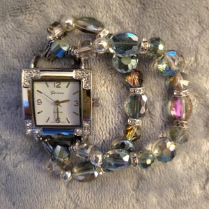 Women’s beautiful green/magenta iridescent stretch watch features a silver square white face with accents in four corners.