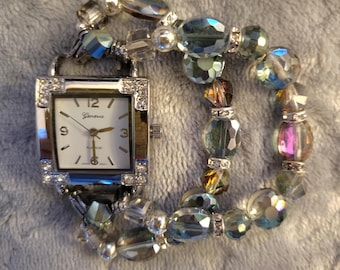 Women’s beautiful green/magenta iridescent stretch watch features a silver square white face with accents in four corners.