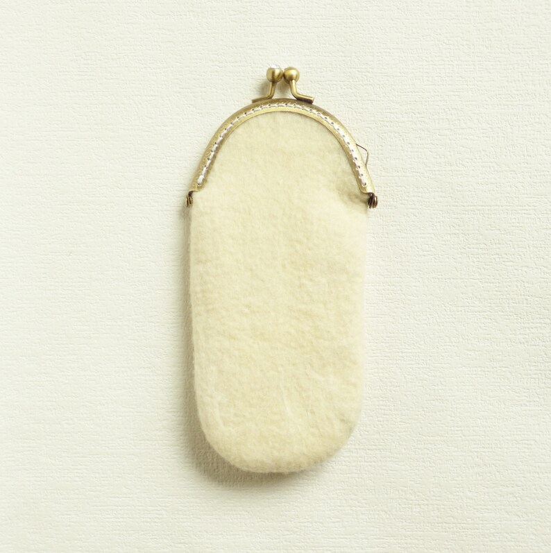 May include: A small, white, fluffy coin purse with a gold metal frame.