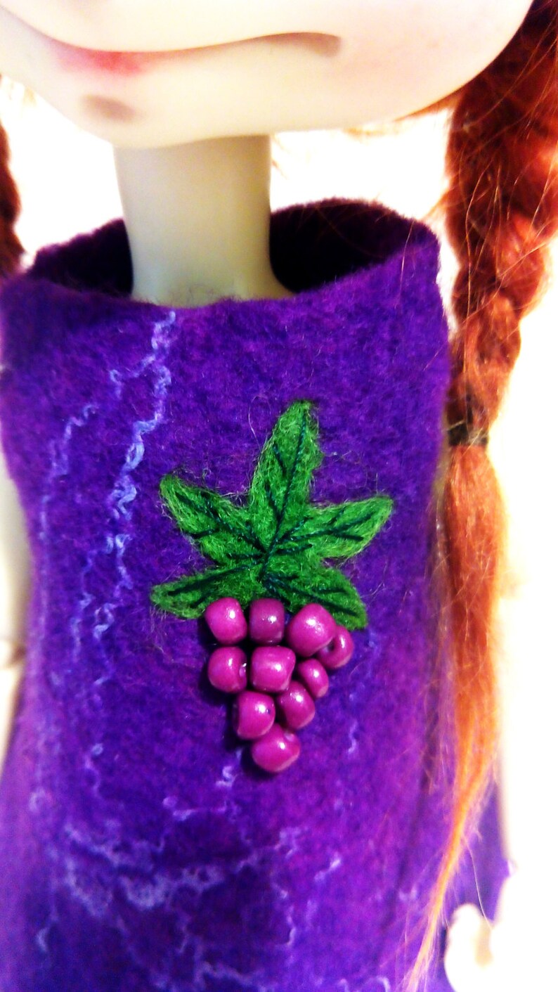 May include: A purple felt doll dress with a green felt leaf and purple felt grapes sewn on the front.